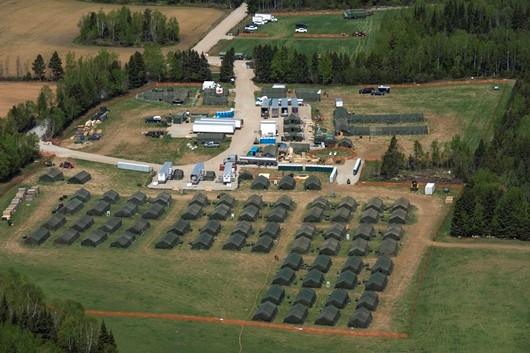 Une vue aérienne du camp érigé par la Force aérienne pour accueillir les troupes de l'opération CADENCE en soutien aux mesures de sécurité du Sommet du G7, à Saint-Irénée, le 31 mai 2018. On y voit des rangées et des rangées de tentes vertes sur un champ de verdure